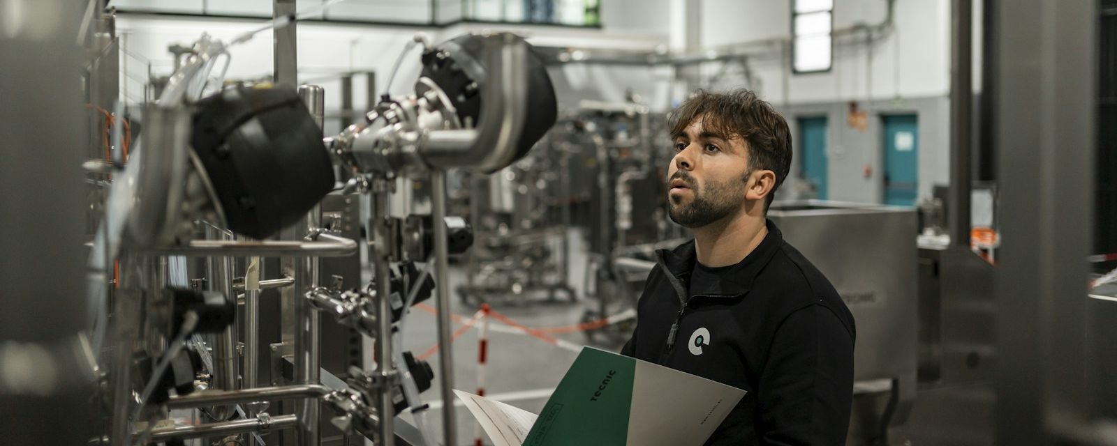 Engineer reviewing a qualification document beside process equipment